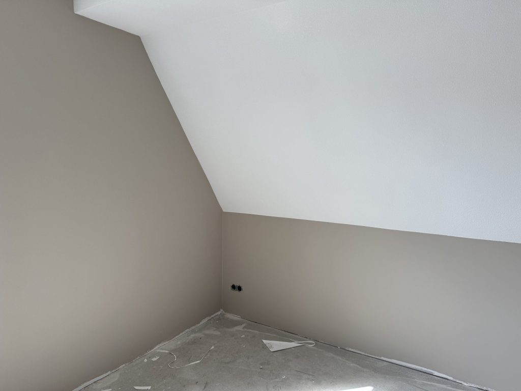 Zolderkamer in een nieuwbouwhuis met taupe wanden en een wit afgewerkte schuine kant